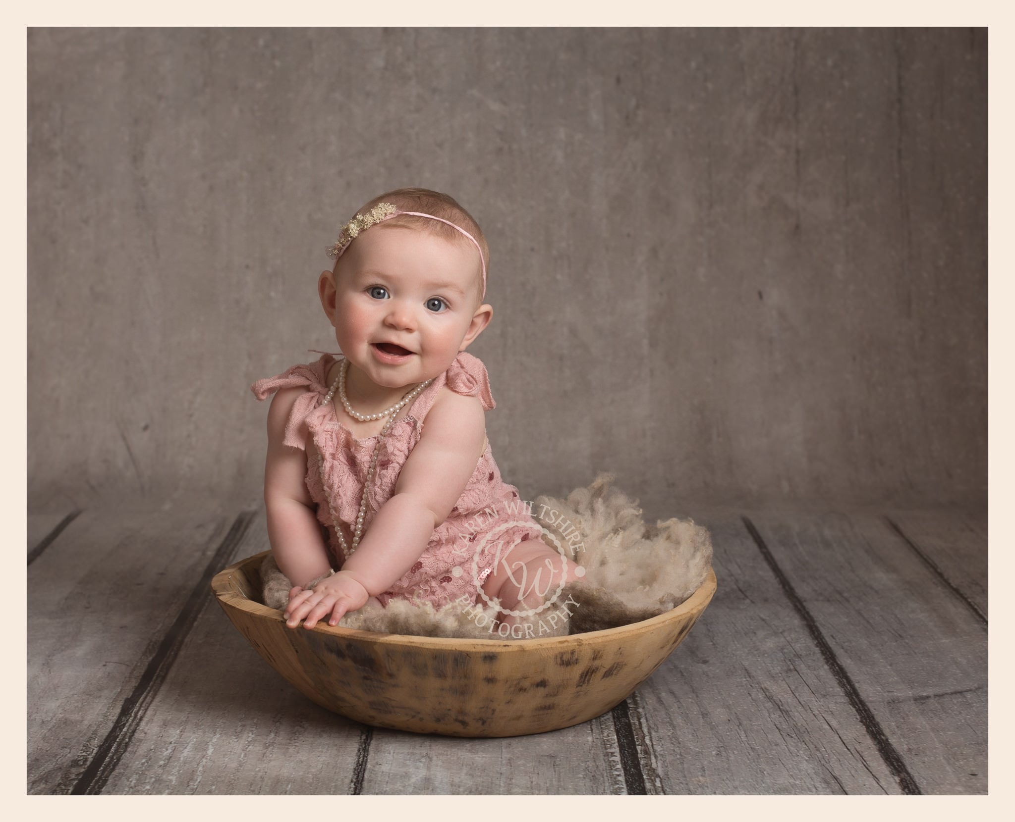 Cute sitting baby girl in wooded bowl