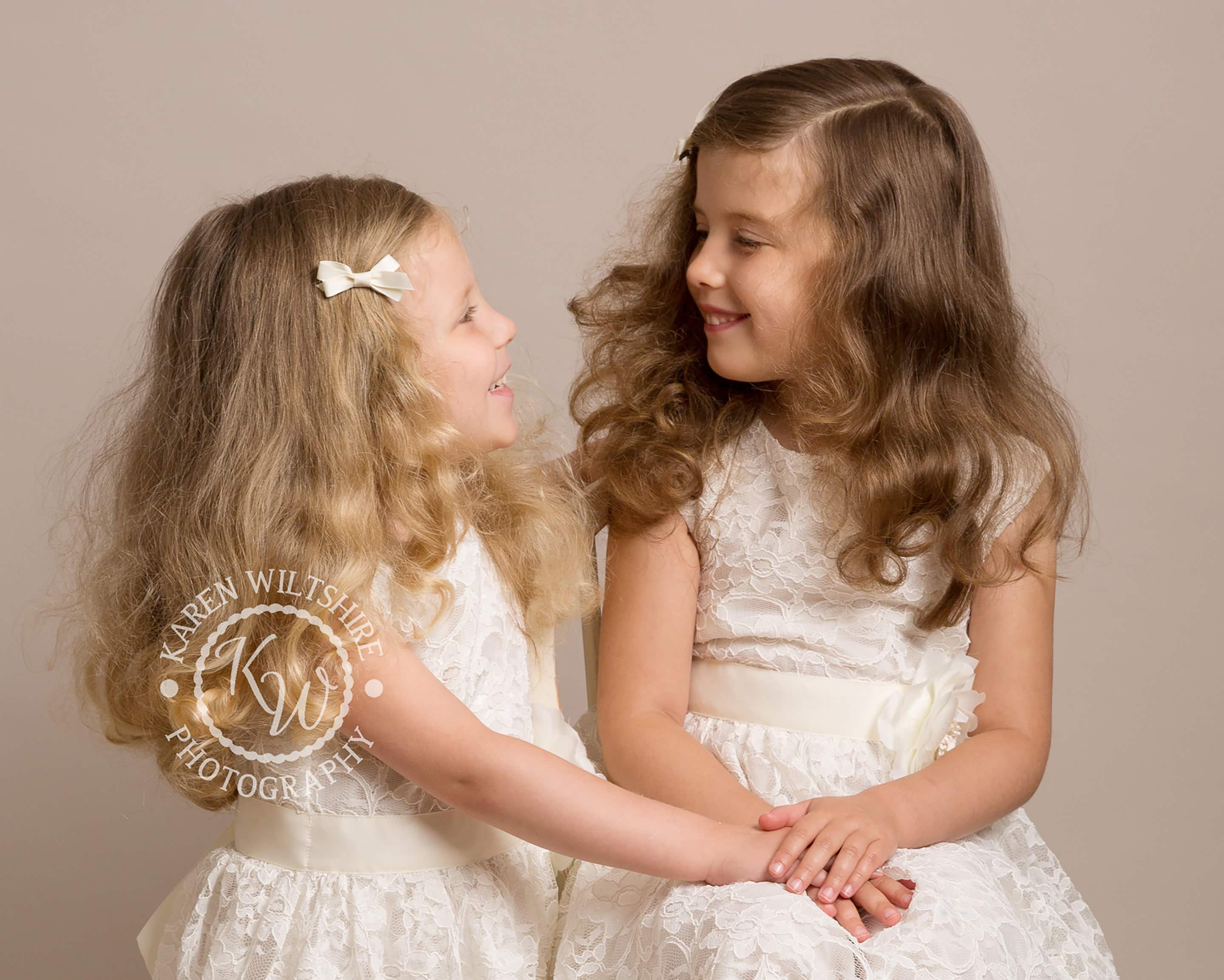 Sisters in white lace dresses smiling