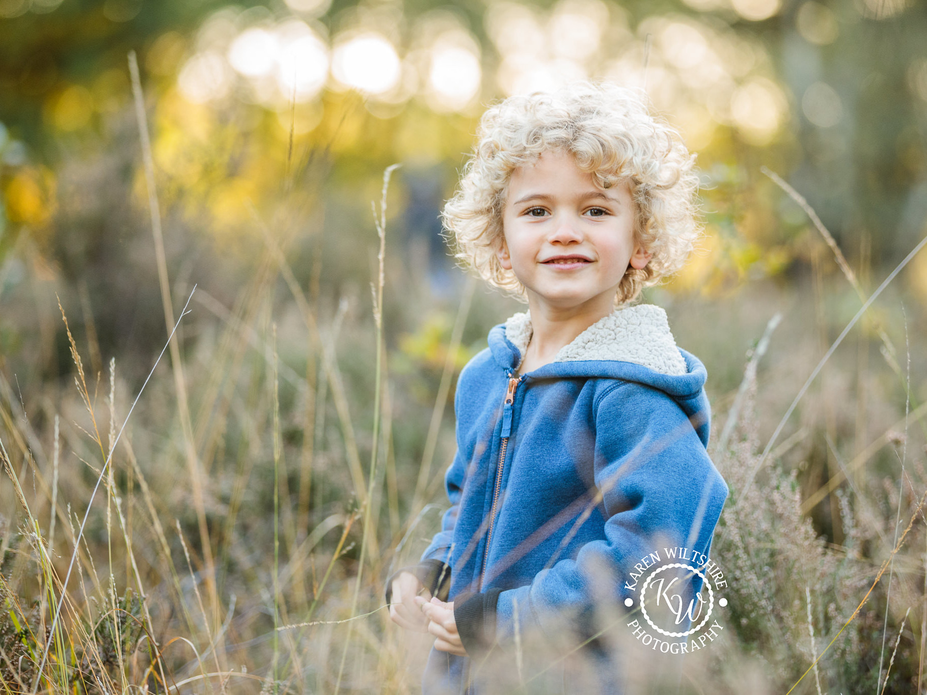 Young boy in long grass smiling for the camera