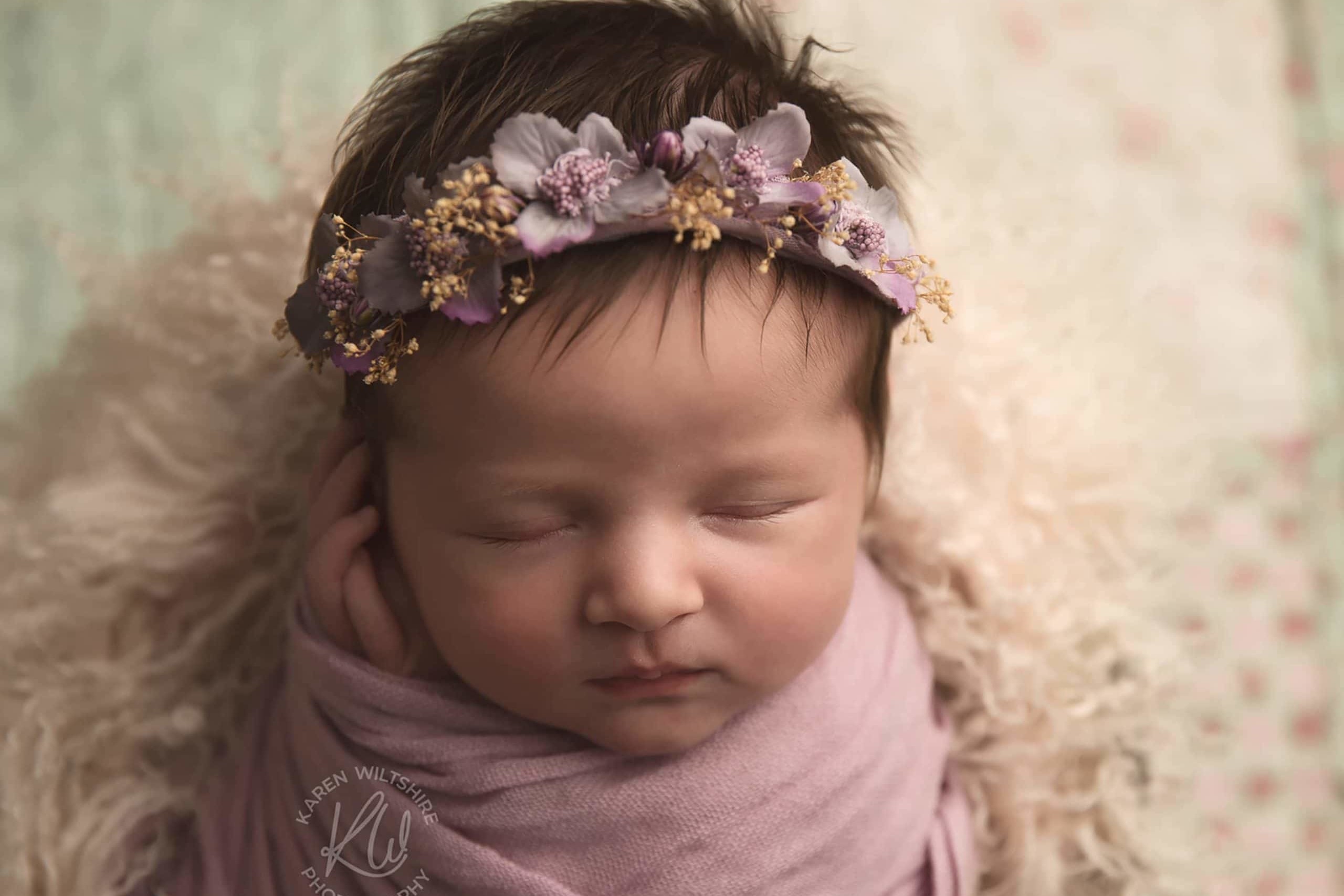 Newborn baby with lots of hair wearing a flower crown