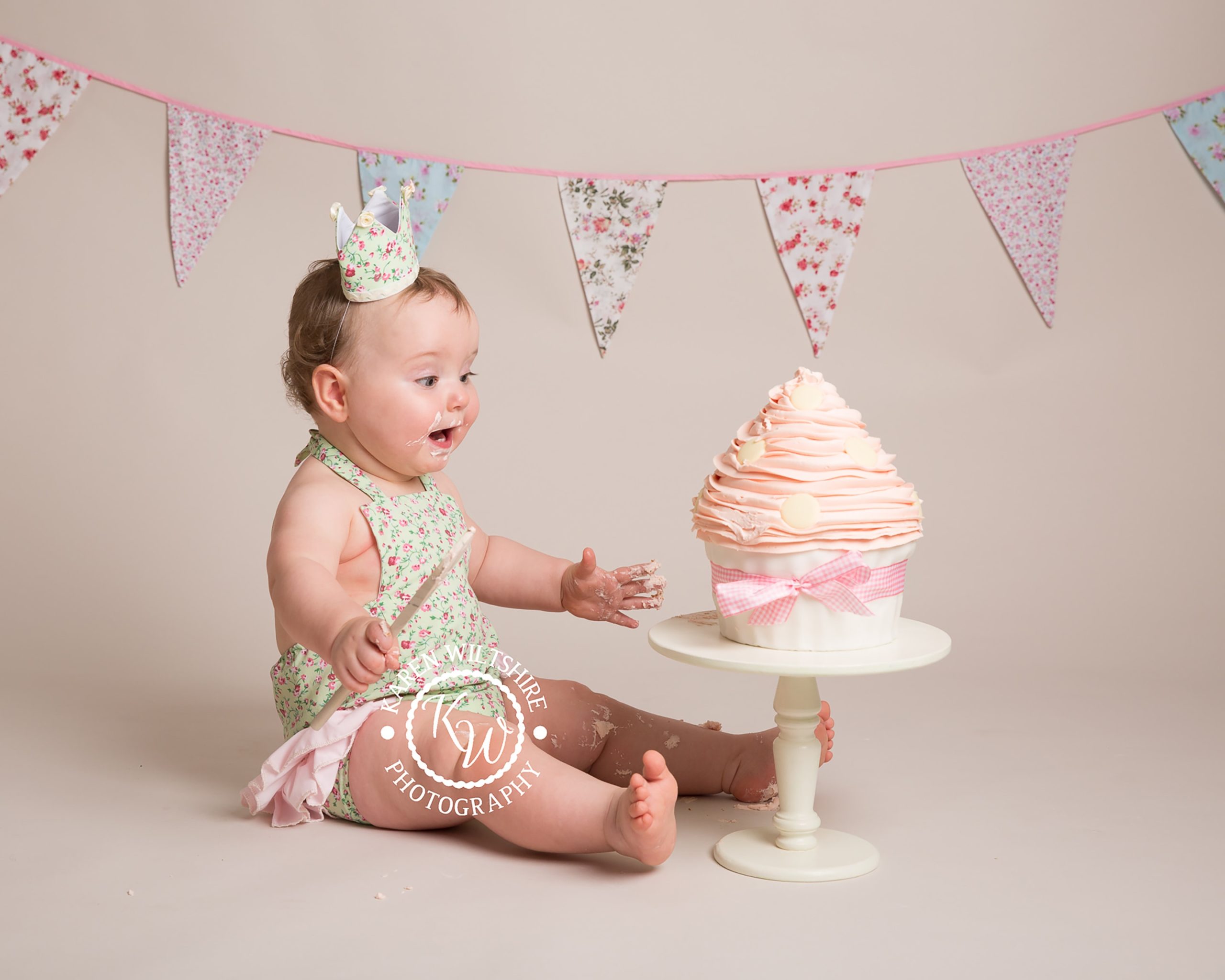 excited baby girl about to tuck into a giant pink cake