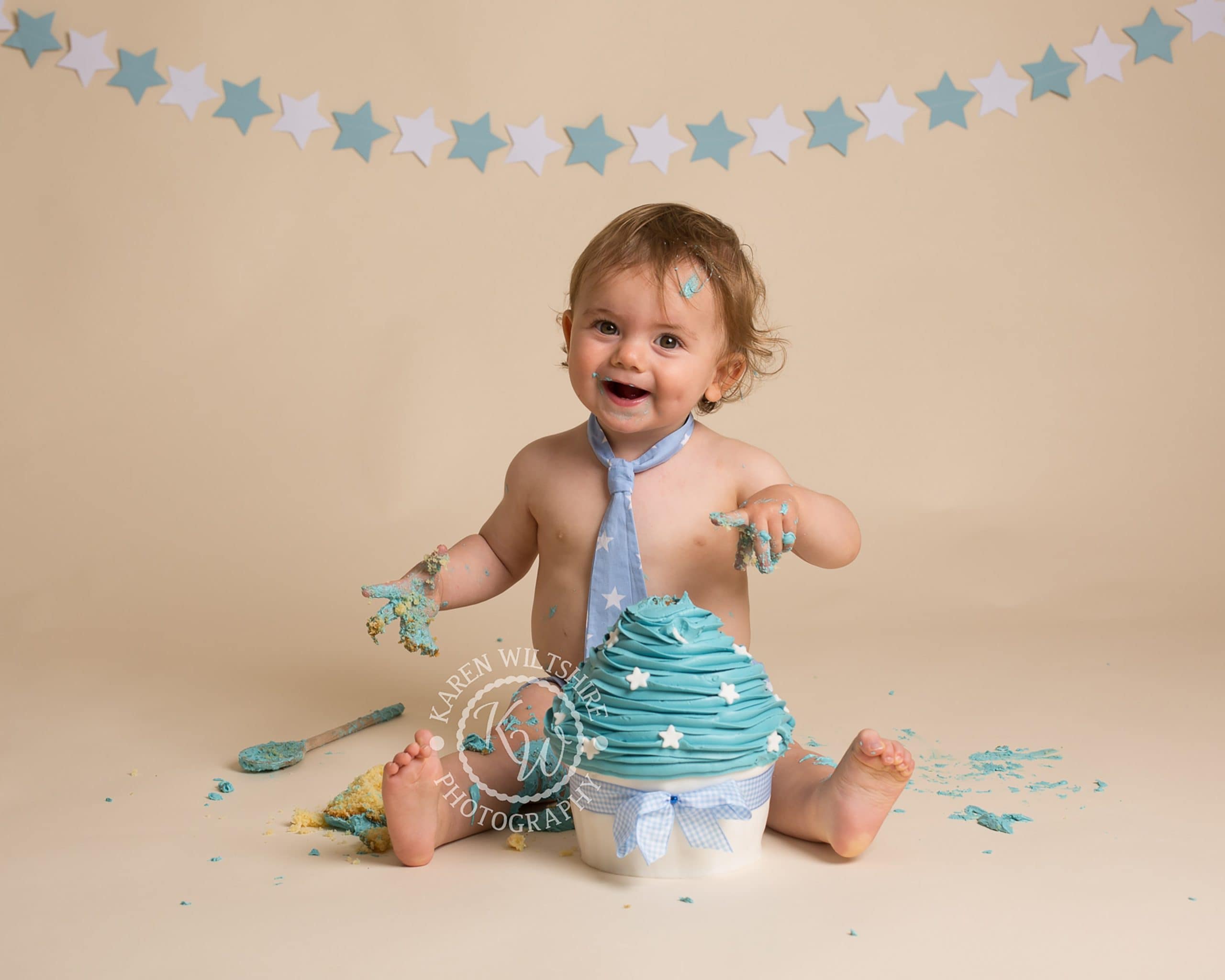 Baby boy covered in cake during his cake smash photoshoot