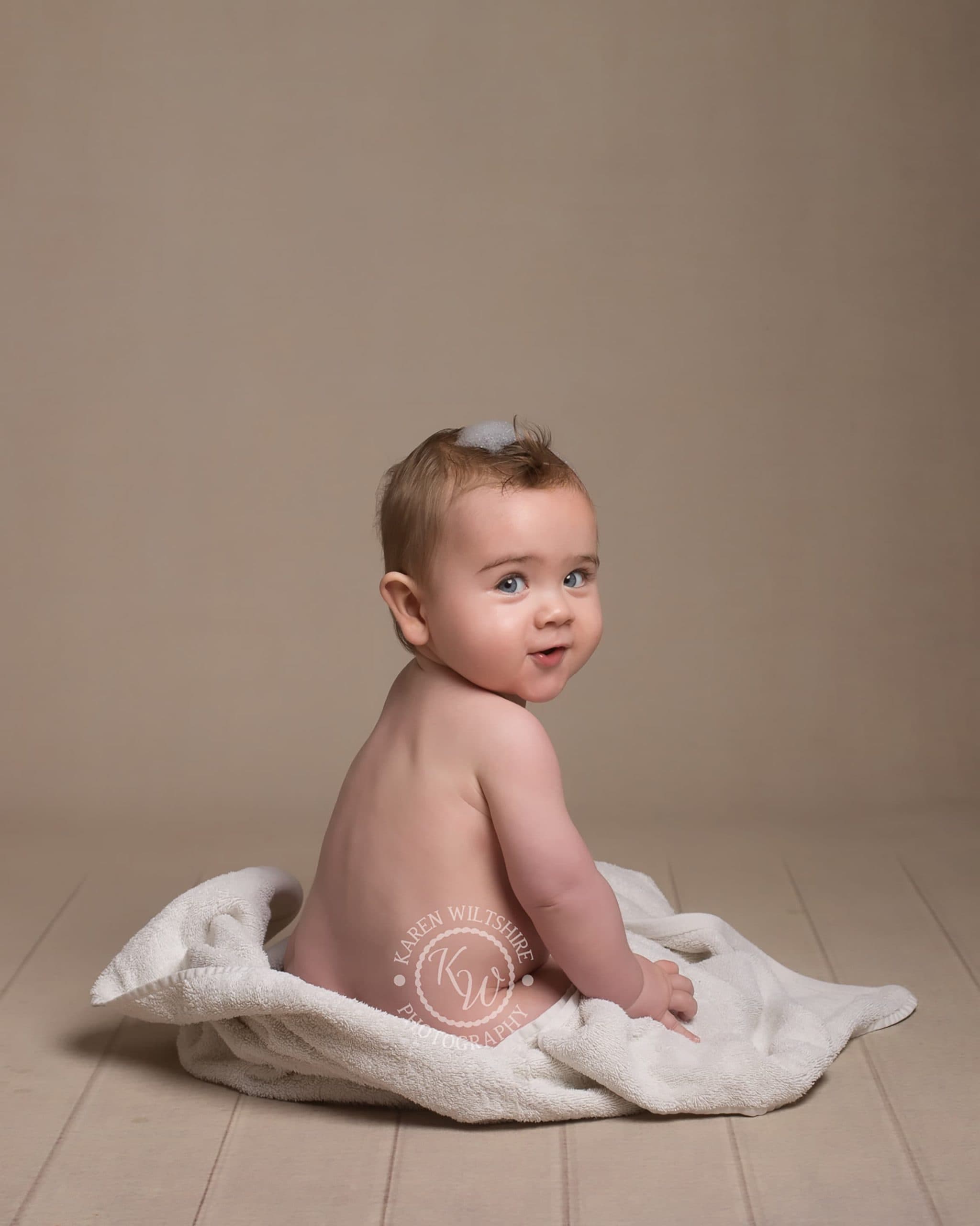 Bare bottomed baby turns to smile at camera
