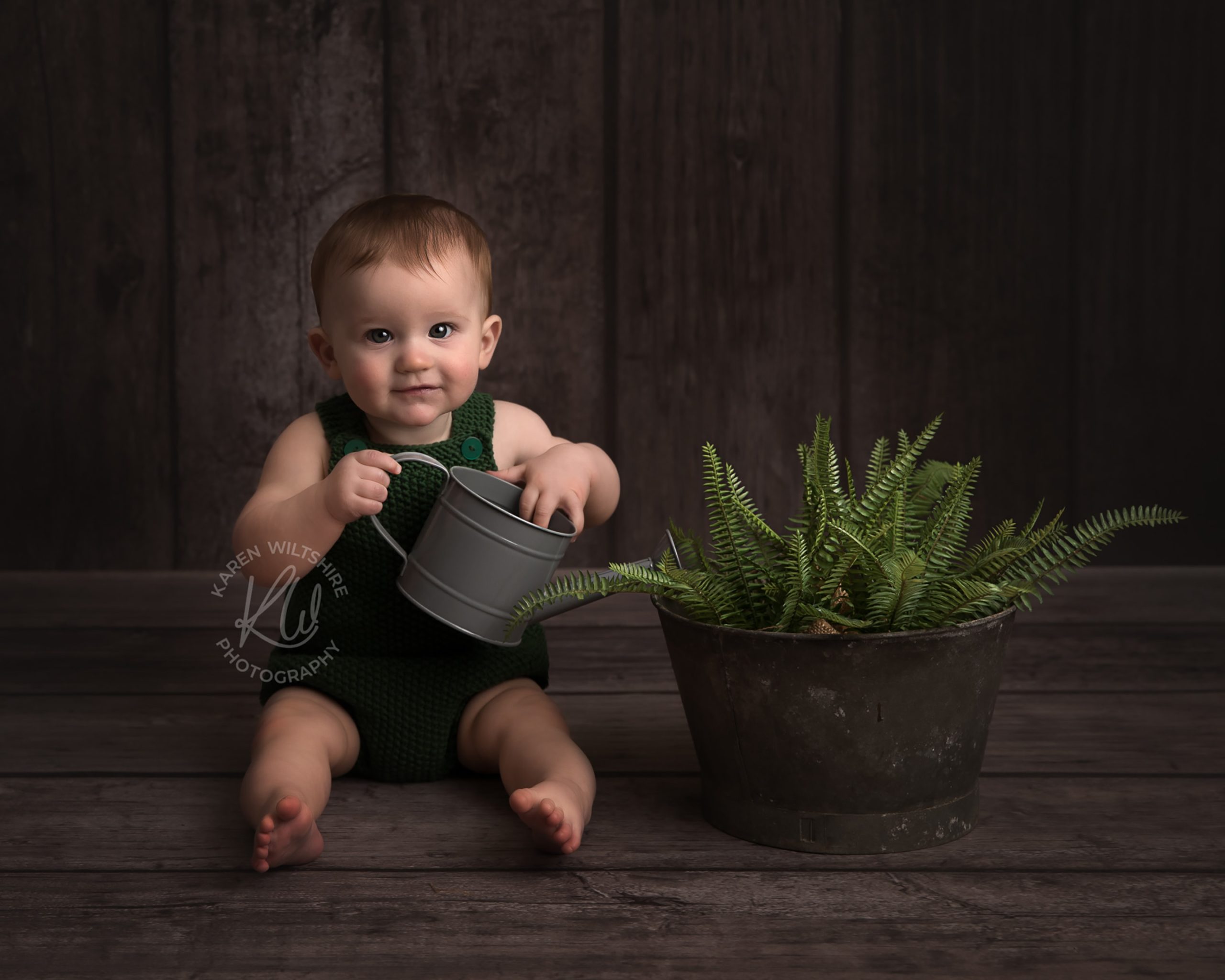 Baby boy watering plants with miniature watering can