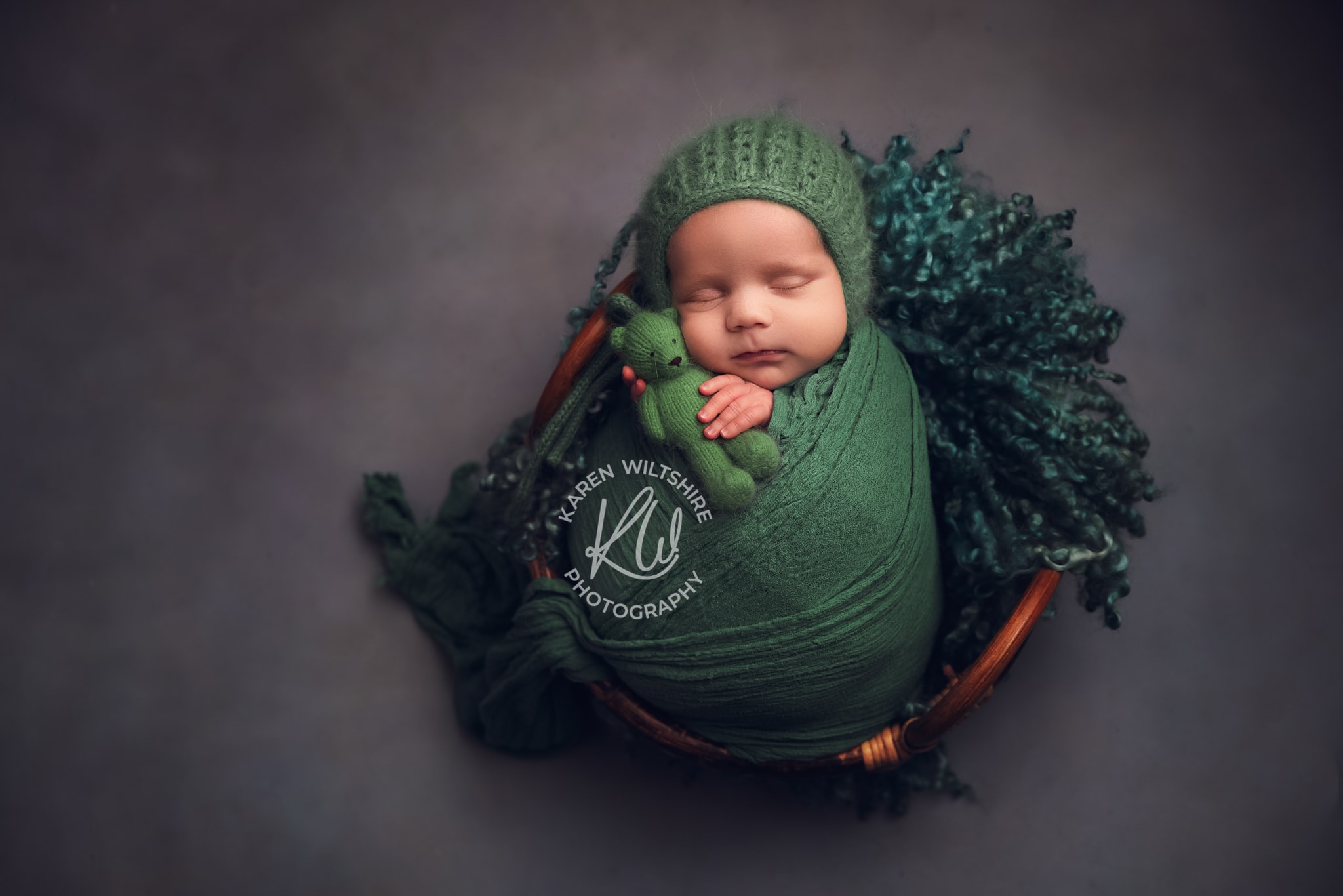 Baby boy cuddling green teddy